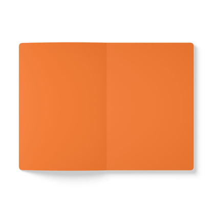 An open, blank creative journal with orange pages lies on a white surface. Viewed from above, a crease shows where the pages are bound. There are no markings, text, or designs, inviting inspiration for daily journaling.