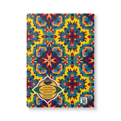 A vibrant African-inspired journal featuring a symmetrical pattern in blue, red, and teal on a yellow background. The gold “AFRO COMFORT SHOP” label and a small QR code add unique touches—perfect for daily journaling or creative notebook ideas.