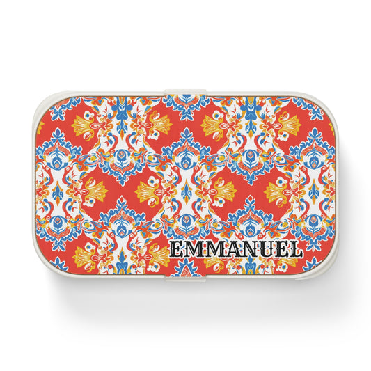 A rectangular, African-inspired bento lunch box with vibrant red, yellow, blue, and white ornamental floral patterns. “EMMANUEL” is boldly printed on the lower right of the lid, and the personalized lunch box features rounded white edges.