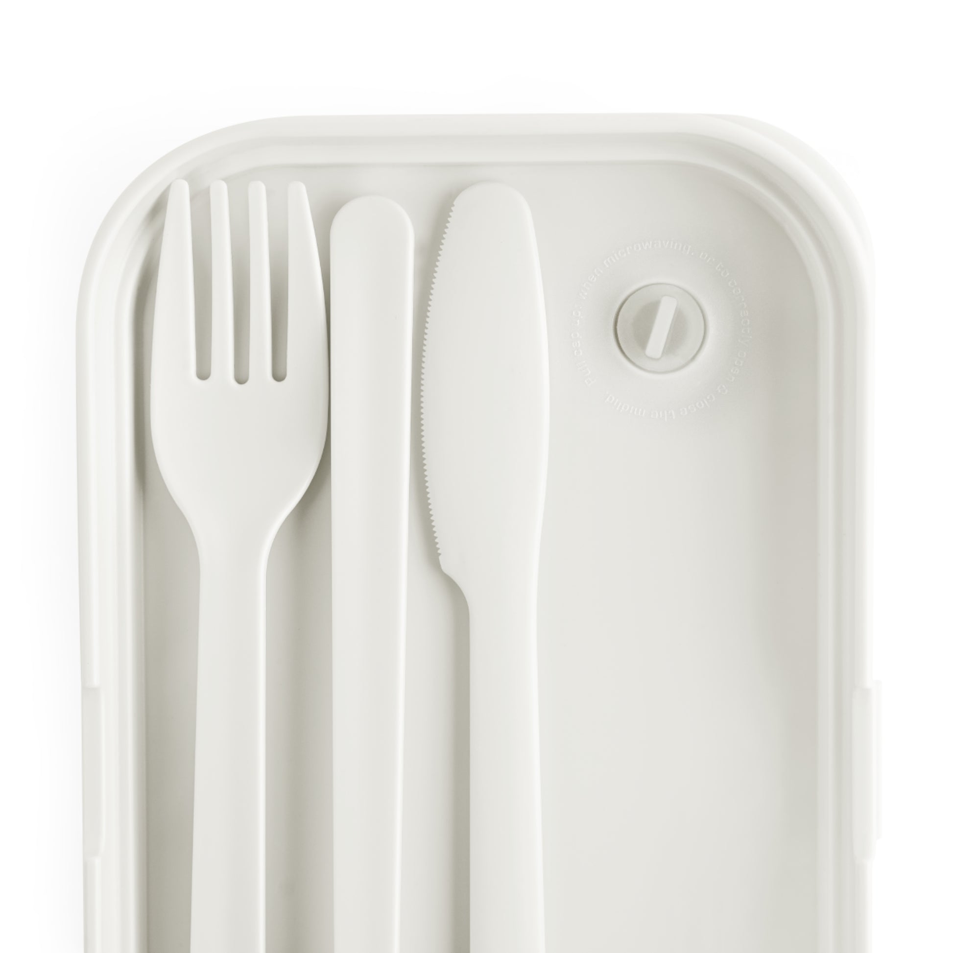 A white plastic fork, knife, and spoon are neatly arranged side by side inside a BPA-free lunchbox with rounded corners. The container features a circular vent with a tab in the top right corner, offering a minimal and modern design.
