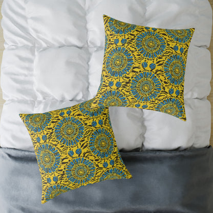 Two vibrant accent pillows with yellow fabric featuring blue and black floral patterns sit on a neatly made bed with a white, quilted comforter and a gray blanket. The pillows, arranged diagonally, add a pop of color to the colorful home decor.