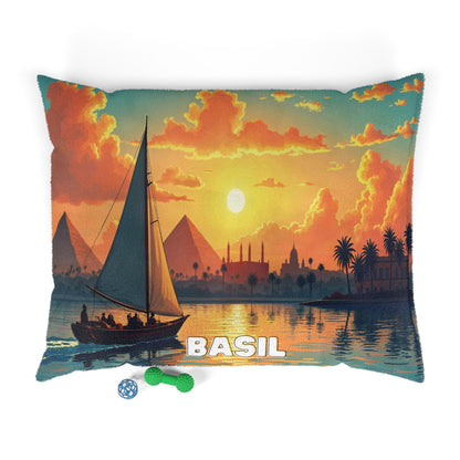 A decorative pillow with an illustration of a sailboat on a river at sunset, featuring pyramids and palm trees in the background. Two dog toys lie nearby, hinting at luxurious comfort—perfect alongside personalized pet beds and cozy spaces.