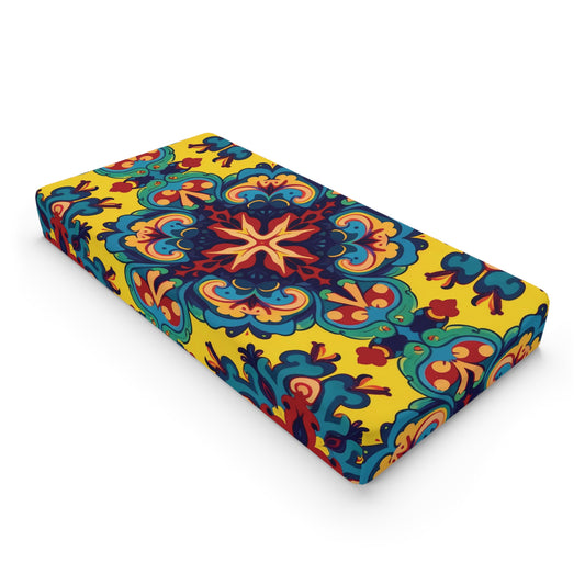 A rectangular cushion with a vibrant, symmetrical floral pattern inspired by African-inspired designs. Bold blue, red, and teal shapes radiate from a star-like center on bright yellow, creating a lively accent perfect for complementing custom changing pad covers.