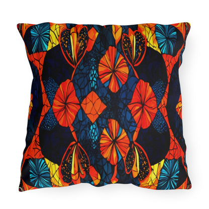 This UV-resistant, water-resistant outdoor pillow features a vibrant abstract pattern with orange, red, blue, and yellow floral and leaf shapes against a dark background, creating a bold and colorful symmetrical design with bright, contrasting colors.