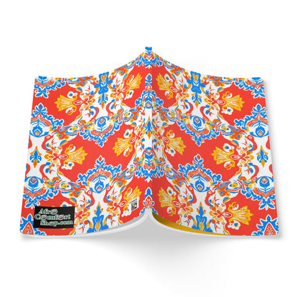 An open book displays a vibrant, symmetrical pattern with red, blue, and yellow floral and ornamental shapes on a white background—perfect for creative journaling or as an African-inspired journal. A small black and green logo in the bottom left reads the contentshop.com.