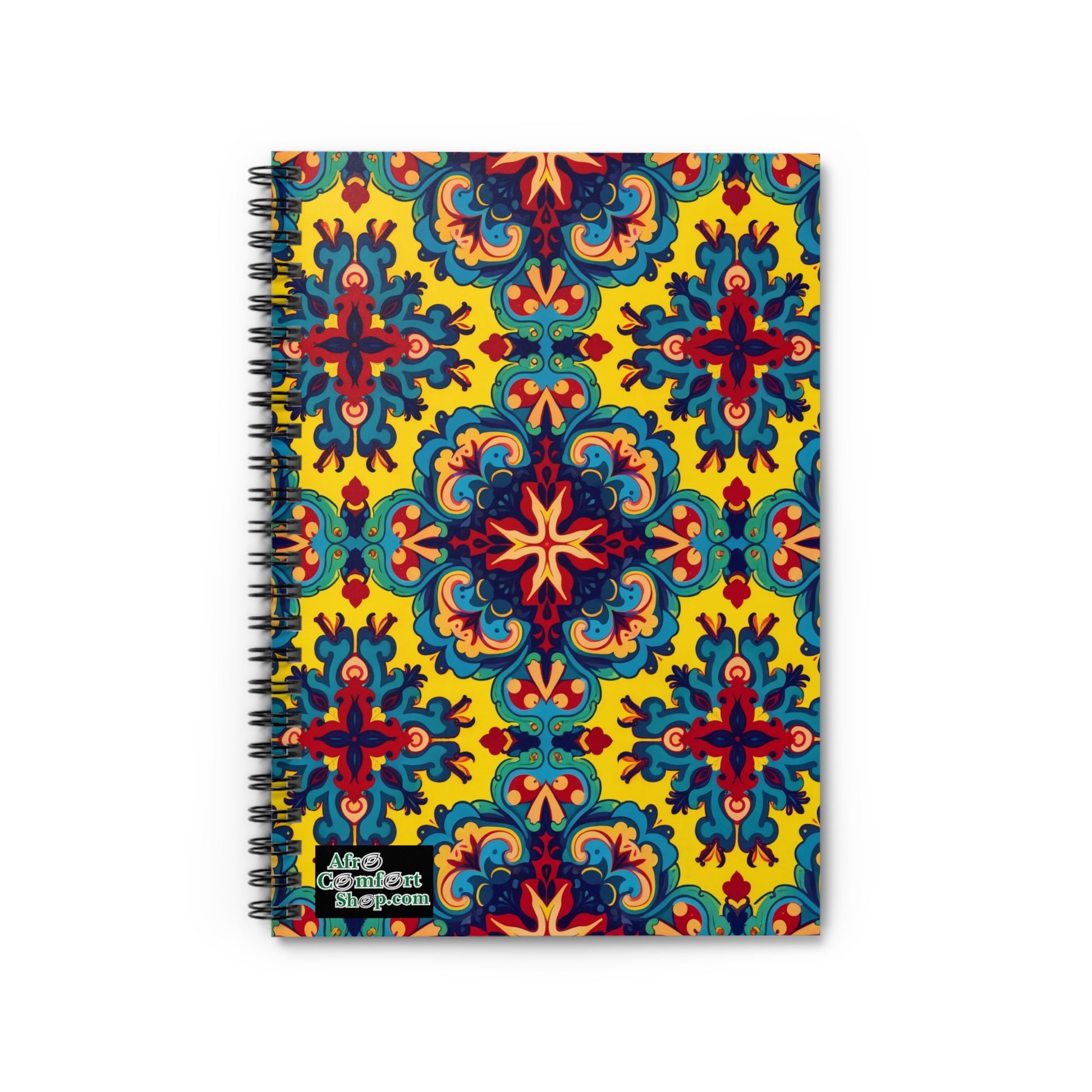 A premium writing journal featuring a vibrant, symmetrical pattern of blue, red, and orange floral motifs on a yellow background. The bottom left corner displays the “Adios Comfort shop.com” logo in white text with a black outline.