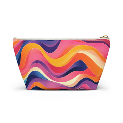 A zippered T-bottom pouch with a colorful, wavy abstract pattern inspired by African-inspired patterns in pink, orange, yellow, purple, and blue. This fabric cosmetic travel bag features a gold zipper and stands upright against a white background.