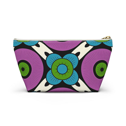 A zippered T-bottom pouch with African-inspired patterns, featuring bold purple circles with green centers and blue, green, and black stylized floral designs on a cream background. The gold-colored zipper runs along the top edge—perfect as a cosmetic travel bag.