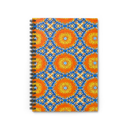 A vibrant designs notebook, this spiral-bound journal features a geometric cover with bold orange and yellow starbursts and blue, white, and orange diamonds on white. The African-inspired spiral notebook is displayed vertically on a white surface.