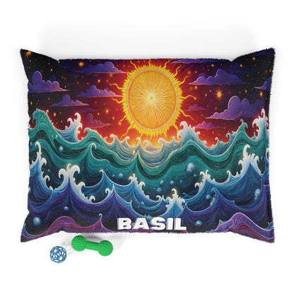 A rectangular pillow with a vibrant design of swirling ocean waves, a radiant sun, and BASIL written in bold white letters at the bottom. Enjoy luxurious comfort with durable construction, plus two dog toys: a green bone and a blue lattice ball nearby.