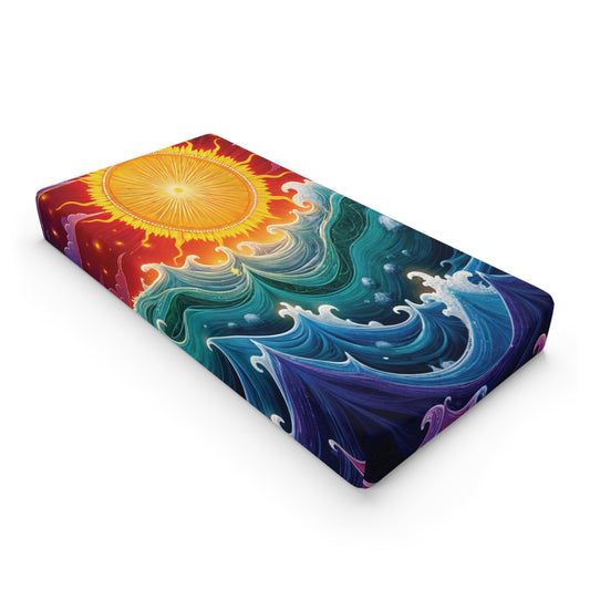 A mattress with a vibrant design featuring a radiant yellow sun in the top left corner, blending into swirling ocean waves in blue, green, and purple—a dynamic contrast reminiscent of African-inspired designs or custom changing pad covers.