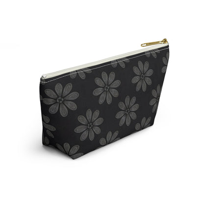 A black T-bottom pouch with a gold zipper pull, featuring a repeating pattern of large, stylized gray flowers reminiscent of African-inspired patterns. The cosmetic travel bag is positioned at an angle on a white background.