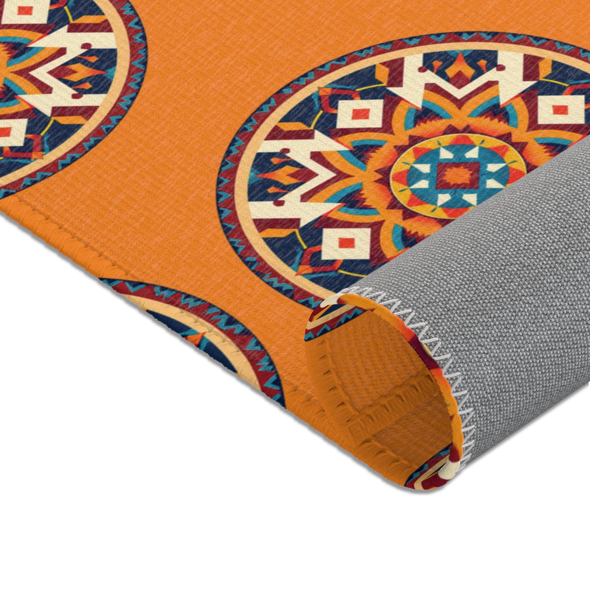A close-up of an African-inspired orange fabric with vibrant, circular geometric patterns in blue, red, white, and yellow. The fabric is partially folded, revealing a gray woven backing with visible white zigzag stitching along the edge.