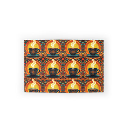 A rectangular mat features a repeating pattern of black coffee cups with swirling steam, set against a warm orange and yellow background with decorative accents. The symmetrical, vibrant design evokes a cozy, vintage feel inspired by culturally inspired designs.