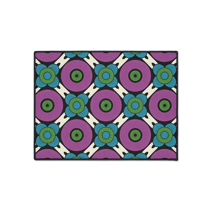 Rectangular rug with a bold, repeating geometric floral pattern inspired by African-inspired aesthetics. Purple circles with green centers, blue petaled flowers, and black outlines sit atop a white background—plus non-slip backing for secure placement.