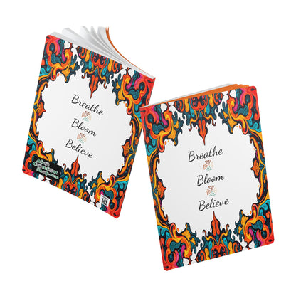 Two square books with colorful, swirled, ornate borders on white covers. The text Breathe Bloom Believe graces these African-inspired journals in elegant script; one open and one closed, each reveals vibrant, abstract designs around the edges.