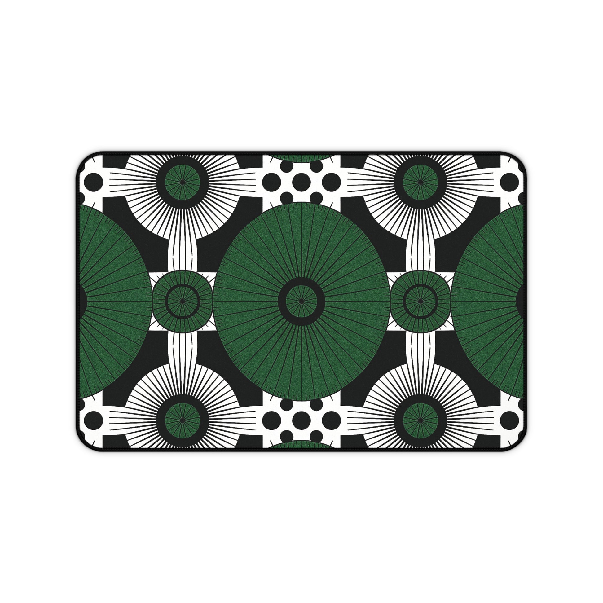 Rectangular neoprene desk mat with a bold geometric pattern: large green circles radiate in a grid, surrounded by smaller black and white circles, sunburst shapes, and black dots on black. A clean, modern colorful workspace accessory with symmetrical design.
