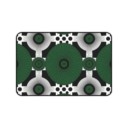 Rectangular neoprene desk mat with a bold geometric pattern: large green circles radiate in a grid, surrounded by smaller black and white circles, sunburst shapes, and black dots on black. A clean, modern colorful workspace accessory with symmetrical design.