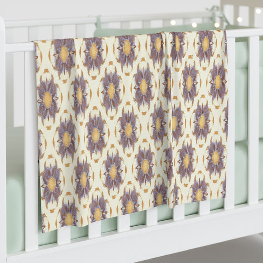 A white crib with mint green bedding has a personalized baby blanket draped over its rail. The blanket features a repeating pattern of large, purple and yellow flowers, adding a cozy and inviting touch to the nursery’s African-inspired decor.