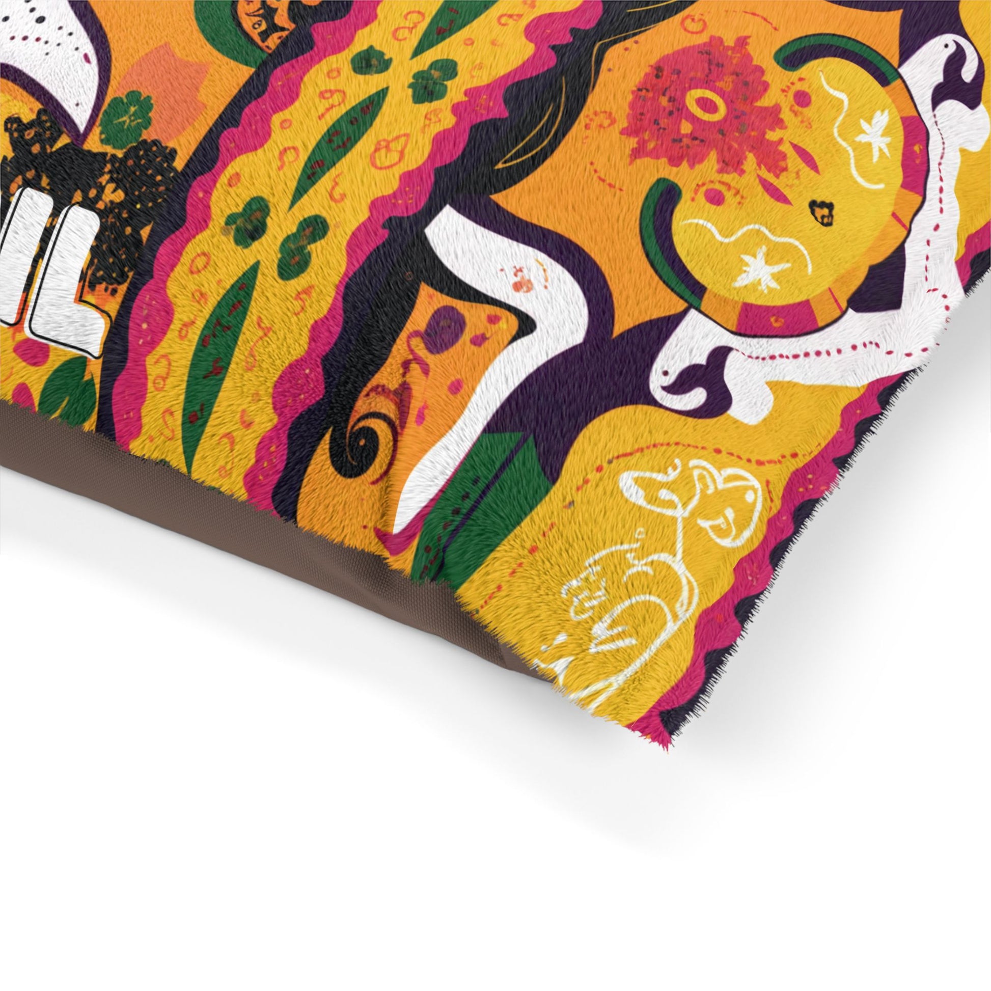 A colorful, African-inspired patterned fabric with abstract floral and animal motifs in orange, yellow, green, white, black, and magenta. The edge shows a brown underside, while whimsical animal shapes are outlined in white.