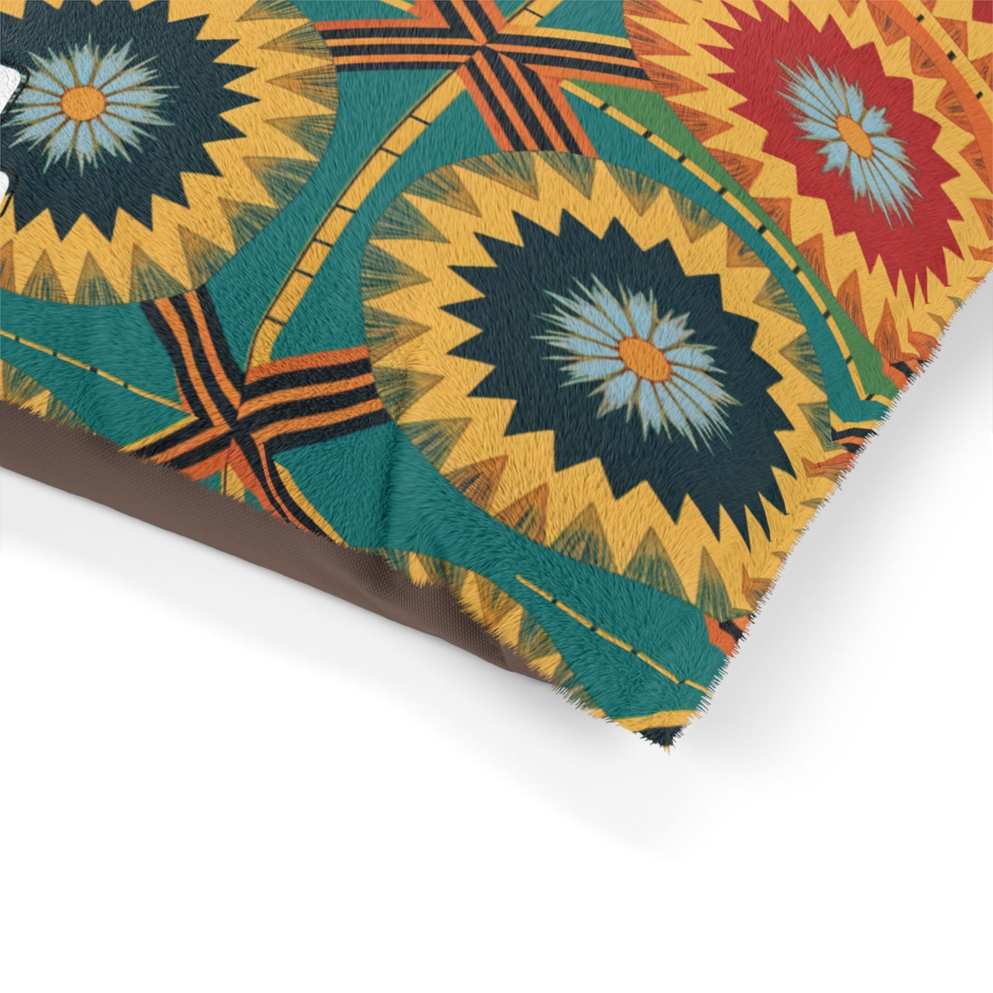 A close-up of a pillow with a vibrant geometric pattern and stylish design. Circular starbursts in yellow, green, red, and blue stand out on a textured fabric with orange and green lines against a brown and teal background.