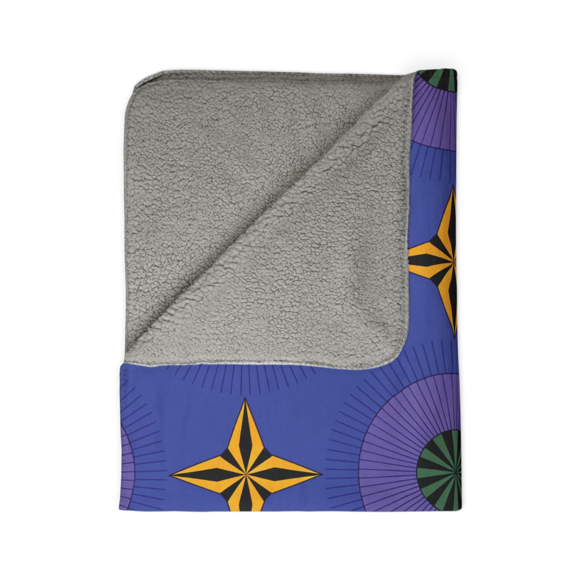 A folded sherpa fleece blanket with a soft, light gray underside. The top side features bold, African-inspired patterns—yellow and black star shapes and radiating purple and green circles on blue—perfect for cozy home decor. One corner reveals the plush sherpa texture.