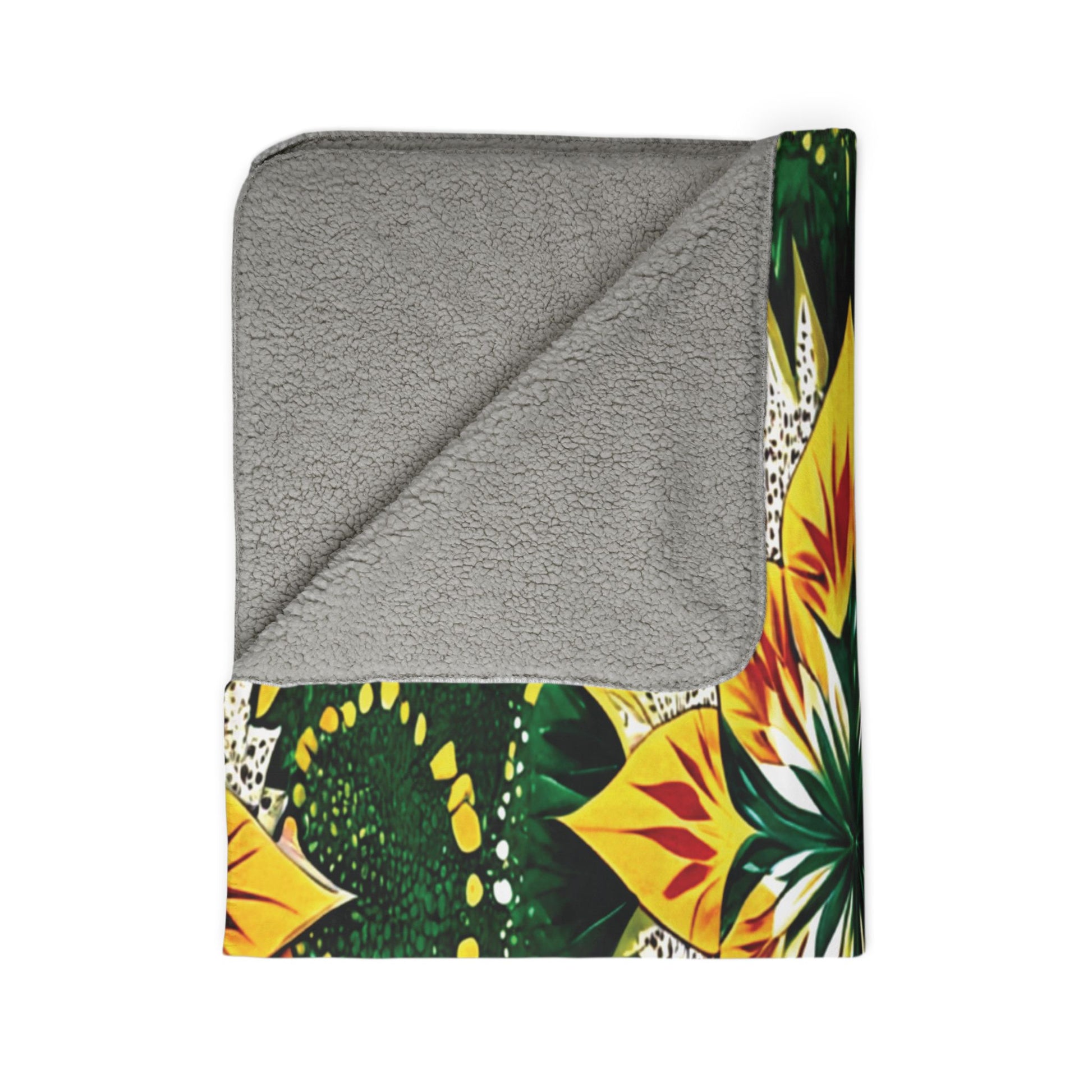A folded blanket with a colorful, bold sunflower pattern in yellow and green inspired by African-inspired fleece blankets, and a soft, textured, solid gray sherpa fleece on the reverse. The top corner is turned down to display both sides on a white background.
