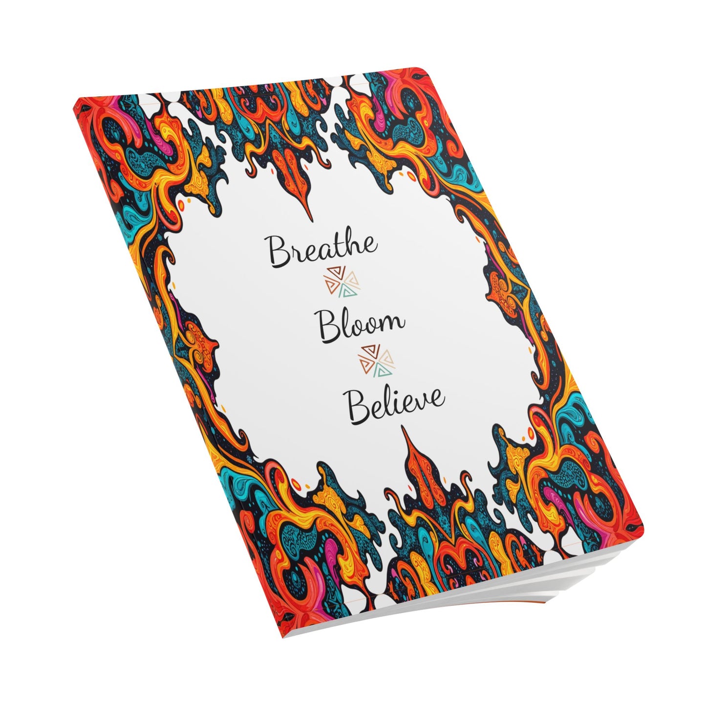 A creative journaling essential, this African-inspired journal with a white cover features “Breathe Bloom Believe” in elegant script, framed by a vibrant swirl of red, orange, blue, and yellow. The journal is slightly angled on a white background.