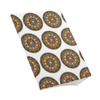 A softcover notebook with a white cover featuring a repeating pattern of colorful, intricate, circular mandala designs in orange, yellow, blue, and black. Perfect for creative journaling, it’s shown at an angle on a plain white background.