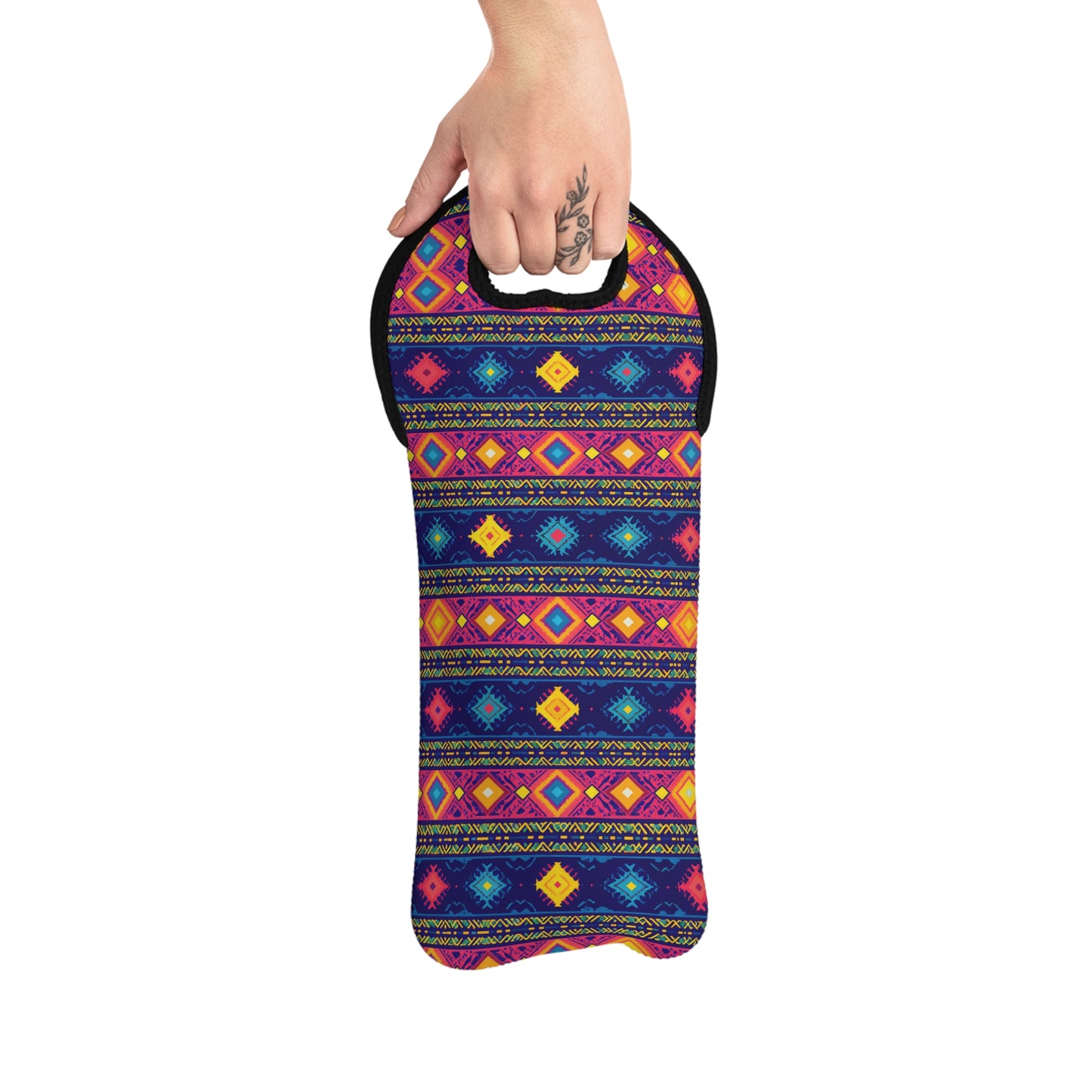 A hand with a floral tattoo holds an African design wine carrier. This neoprene wine tote showcases horizontal rows of geometric shapes in vivid pink, yellow, blue, and orange on a dark background, with a rounded handle and insulated bottle holder.