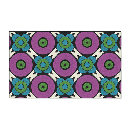A rectangular non-slip rug with a repeating floral pattern. Large purple circles with dark centers are surrounded by smaller blue-green flowers on cream, separated by black lines, creating a bold, geometric, retro look perfect for African-inspired home decor.