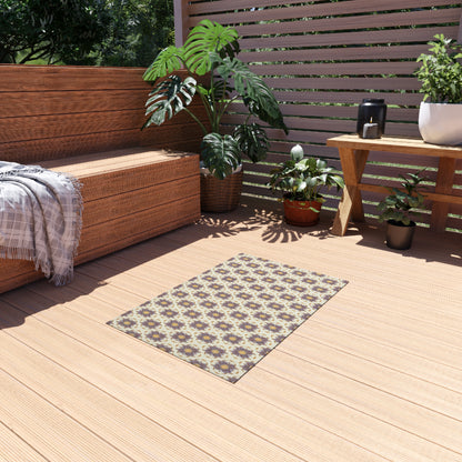 A cozy wooden patio with a bench draped in a gray plaid throw, green potted plants, and an African-inspired patterned rug on the deck. Sunlight streams through slatted wooden fencing in the background, creating a warm and inviting retreat.
