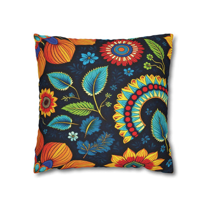 A square pillow with a dark background features vibrant, colorful floral patterns inspired by African pillowcases. Large orange, red, and yellow flowers with blue and green leaves create a lively, bohemian vibe.