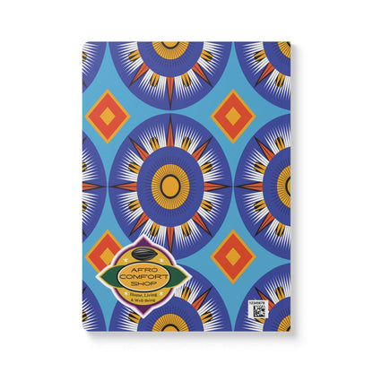 A vibrant blue African-inspired journal with bold orange, navy, and yellow circles and red and yellow diamonds. Its gold and green label reads “AFRO COMFORT SHOP Home Living & Way Better”—perfect for daily journaling.