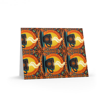 A patterned greeting card stands upright, featuring a culturally inspired design of black cups with swirling yellow steam on vibrant sunburst backgrounds, framed by decorative borders with blue, green, and orange accents.