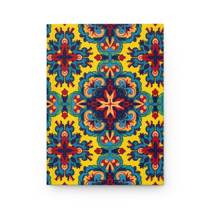 A culturally-rich notebook with a vibrant cover featuring an ornate, symmetrical pattern in blue, red, teal, and orange on yellow. The design blends floral and geometric shapes into a repeating, kaleidoscopic motif.
