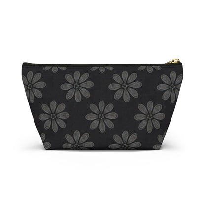 A black T-bottom pouch featuring a repeating pattern of large, stylized gray flowers with six textured petals and dotted centers. The gold zipper and wide base make it a chic cosmetic travel bag with subtle African-inspired patterns.