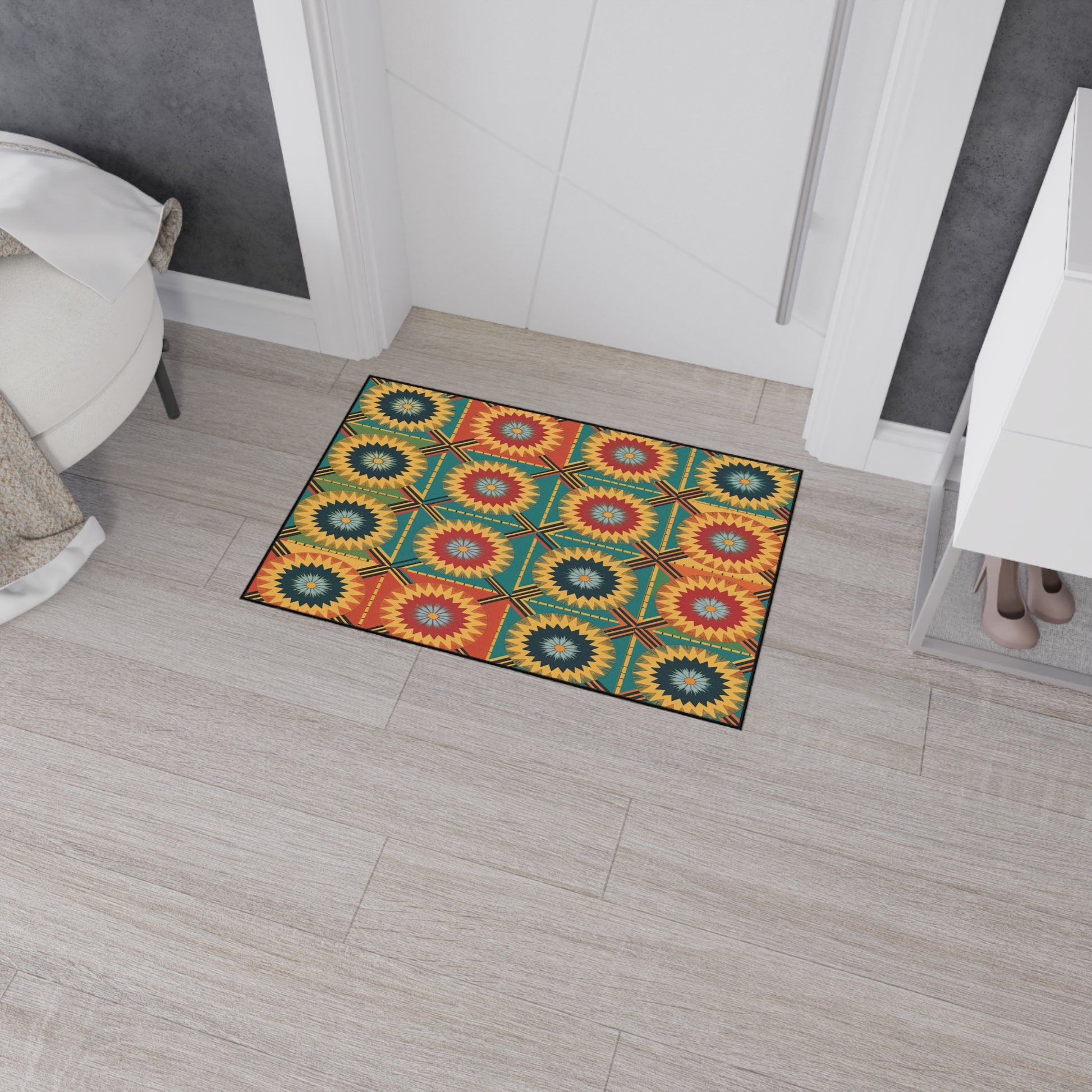 A colorful rectangular rug with a geometric sunburst pattern inspired by African-inspired aesthetics in yellow, red, green, and blue lies on a light wood floor in a modern entryway next to a white cabinet, shoes, and a round upholstered stool.