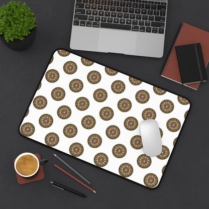 A neatly arranged black desk with a laptop, small potted plant, notebooks, pencils, coffee, and a white mouse on an ergonomic neoprene desk mat featuring a repeating colorful mandala pattern—a vibrant workspace accessory.