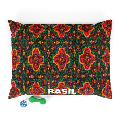 A rectangular pillow with a colorful red, green, and orange geometric floral pattern offers luxurious comfort. The word BASIL is printed in white at the bottom center. Two dog toys—a green rope bone and a blue ball—are nearby on a white background.
