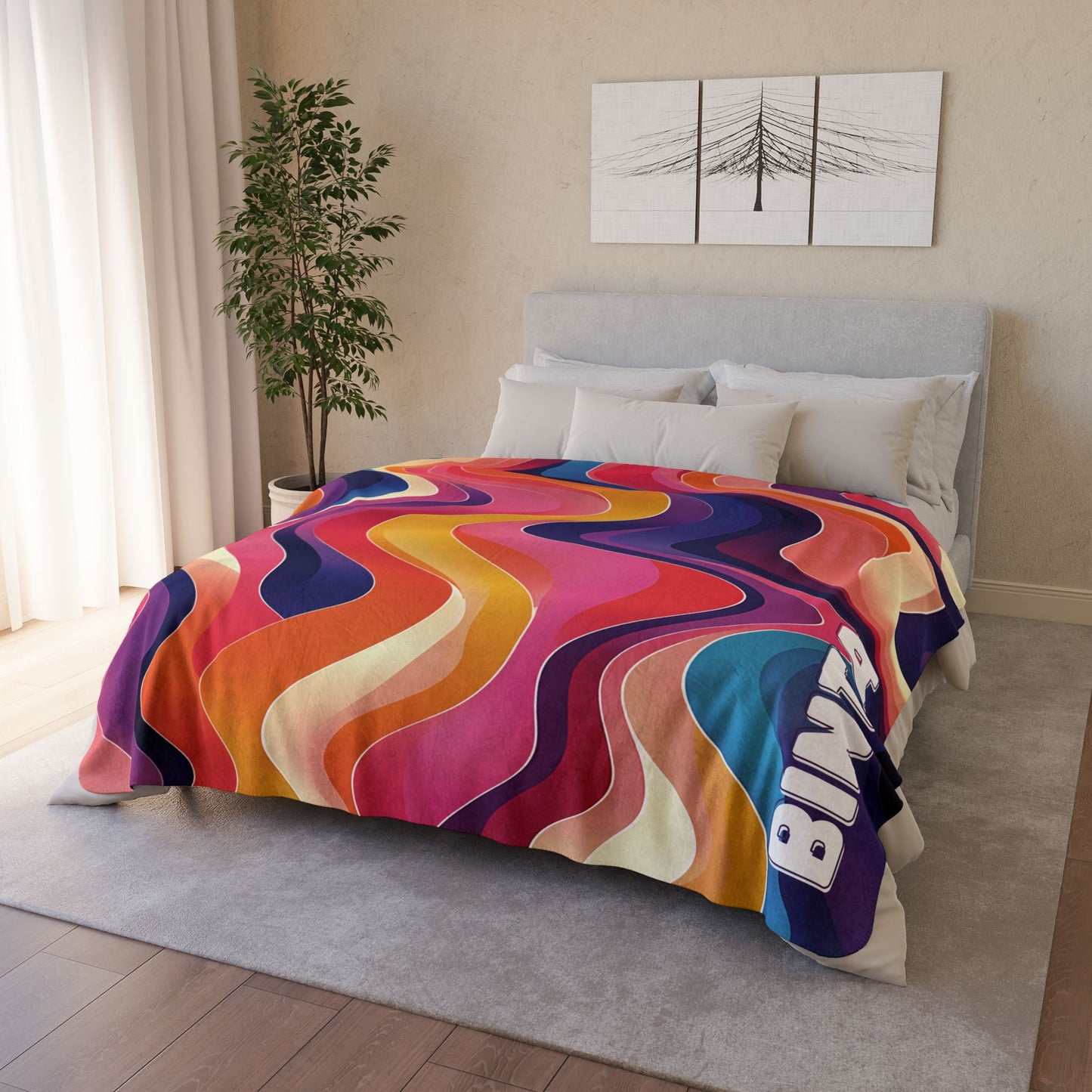 A modern bedroom with a bed covered by an African-inspired fleece blanket in vibrant wavy patterns and the word BING. There’s a potted plant, white curtains, and minimalist wall art above the bed for a cozy touch.