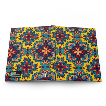 An open notebook with a vibrant cover featuring a repeating, ornate floral pattern in red, blue, and green on a yellow background. This African-inspired journal includes a small Adult Coloring Book logo and QR code on the lower left back cover.