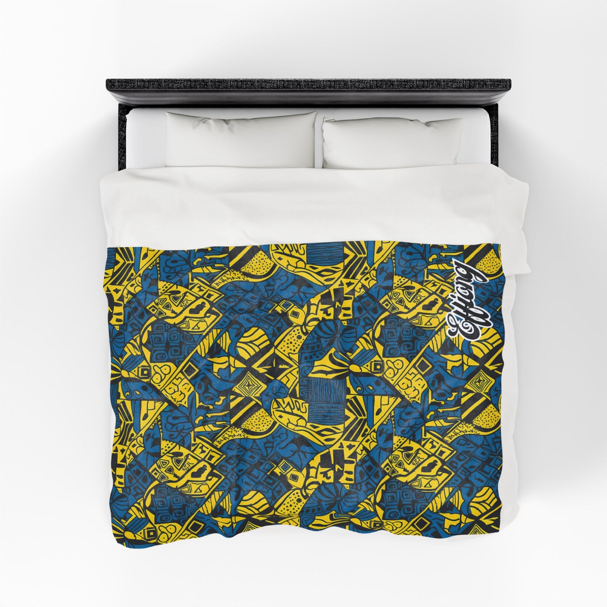 Overhead view of a bed with white pillows and a personalized velveteen blanket featuring a vibrant blue and yellow geometric and abstract pattern. Overlapping shapes, lines, and “Respect” in white script highlight this unique custom gift.
