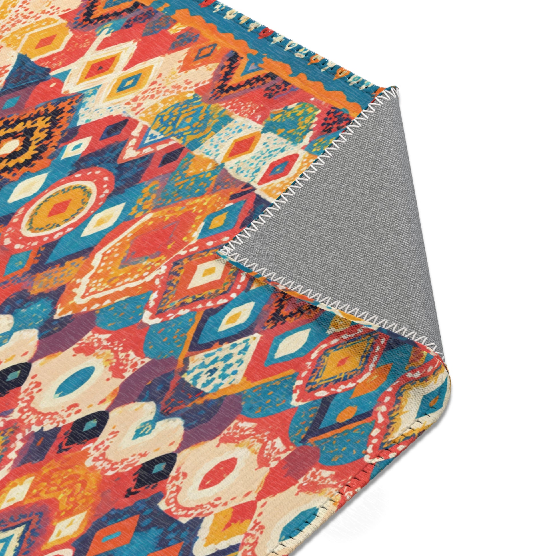 A colorful woven rug with a geometric, diamond-shaped pattern in red, orange, blue, and cream tones. Its flipped corner reveals a gray backing with zigzag stitching—perfect for stylish home decor and crafted from durable polyester rugs material.