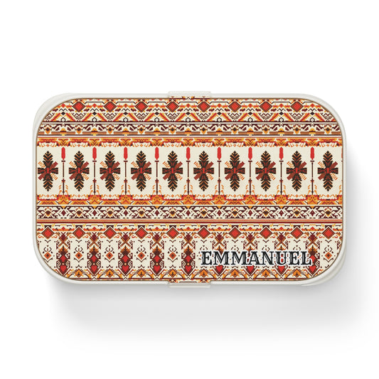 A rectangular, African-inspired lunch box with a red and brown geometric and leaf pattern on a cream background. EMMANUEL is printed in bold black letters in the bottom right corner. The case has rounded edges and a white border.