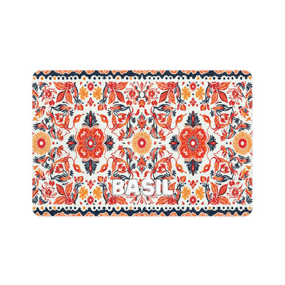 A colorful rectangular mat with a repeating African-inspired floral pattern in red, orange, navy blue, and black on a white background. Large flowers and leaves are prominent, and BASIL is written in bold white letters in the center.