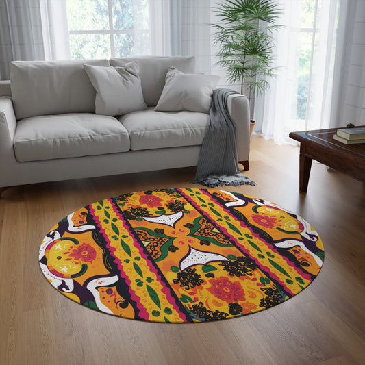 A cozy living room with a light gray sofa, sheer white curtains, and a wooden coffee table. An African-inspired round rug with orange, yellow, black, and purple floral patterns adds vibrant color to the wooden floor.