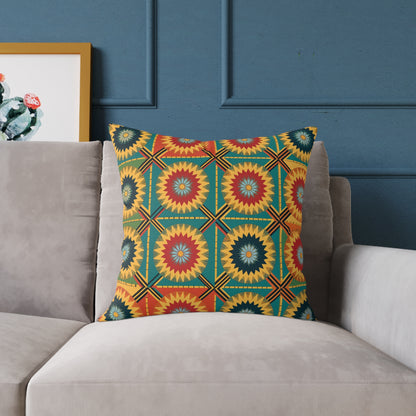 A colorful accent pillow with a geometric, starburst pattern in red, yellow, green, and blue sits on a light gray couch. The background wall is dark blue, and a framed cactus artwork is partially visible to the left.