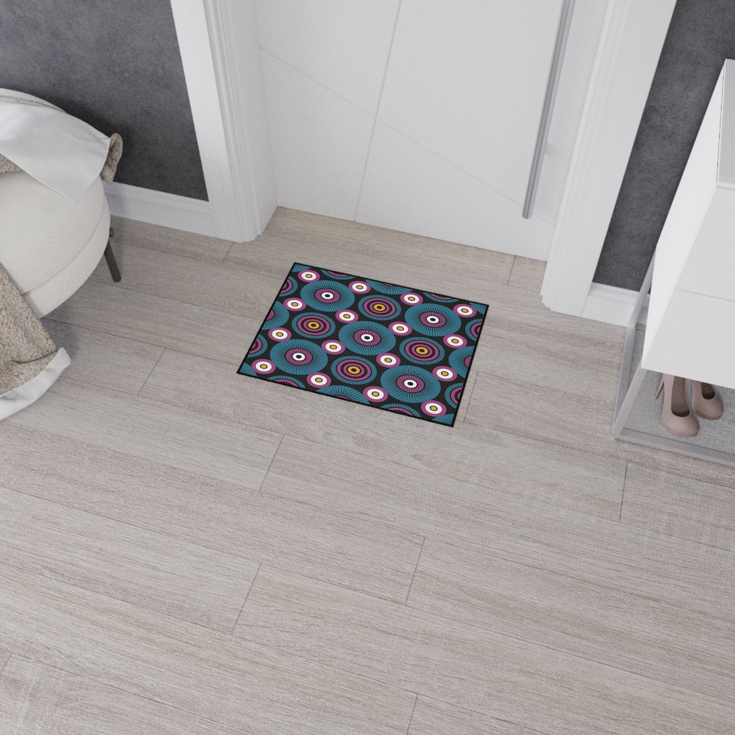 A small rectangular custom floor mat with a colorful circular pattern and non-slip rubber backing sits in front of a white door on light wood flooring, adding both safety and flair to this modern, tidy entryway.