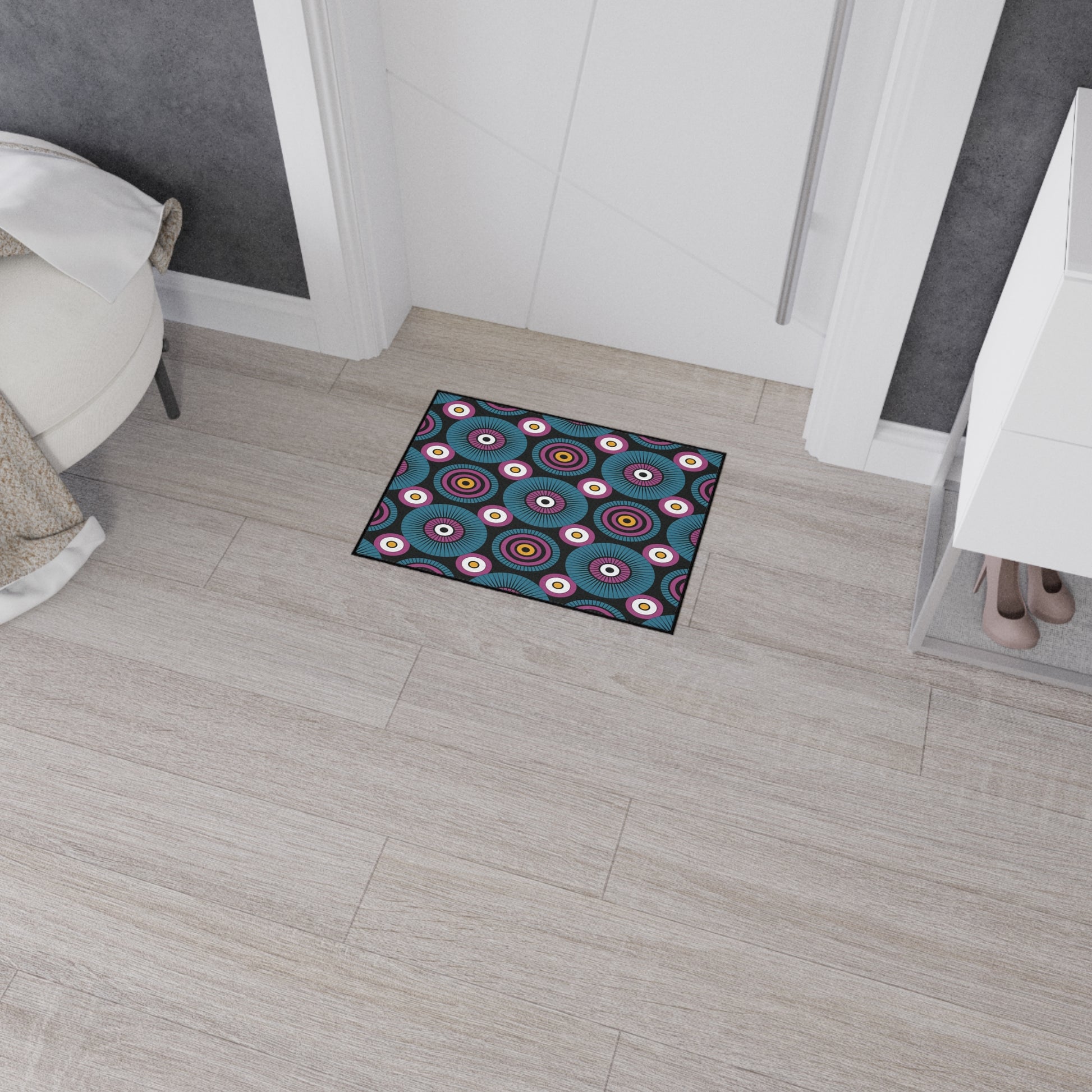A small rectangular custom floor mat with a colorful circular pattern and non-slip rubber backing sits in front of a white door on light wood flooring, adding both safety and flair to this modern, tidy entryway.